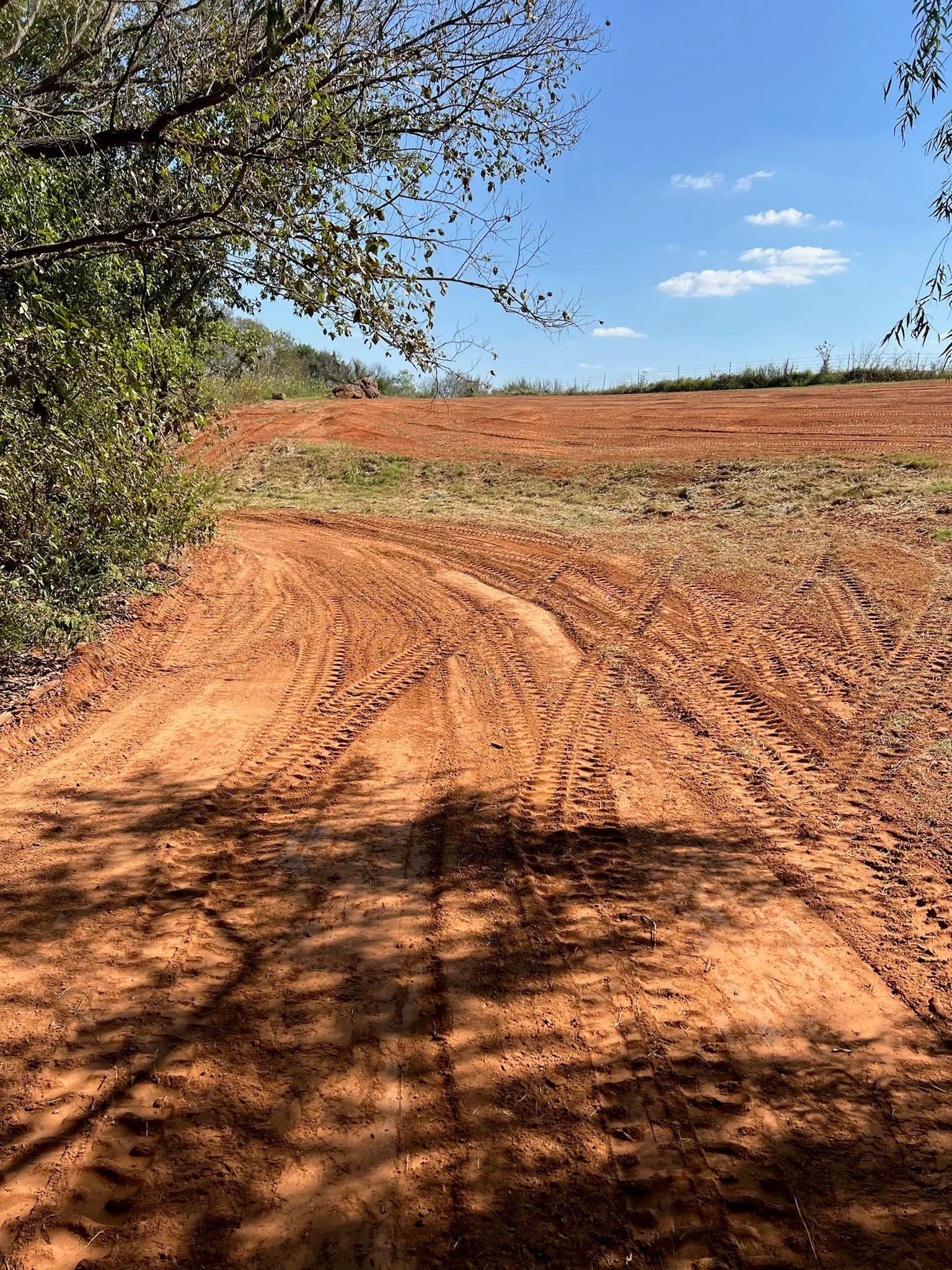 Graded dirt lot with machine tracks and cleared land ready for development