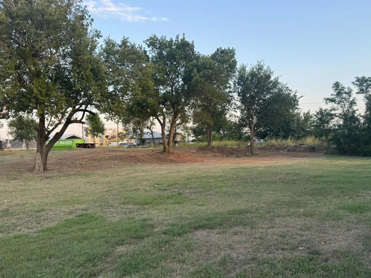 Cleared lot with mature trees and graded soil ready for construction