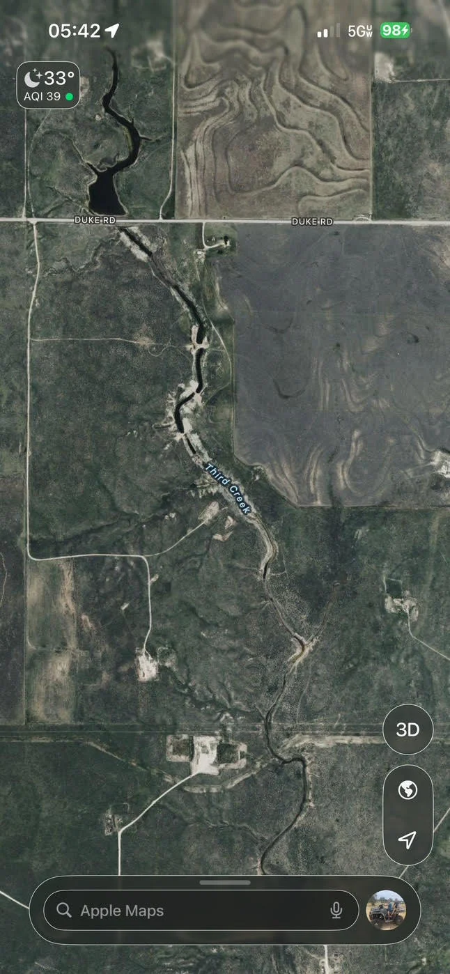 Aerial view of cleared land with creek and excavation patterns near Duke Road