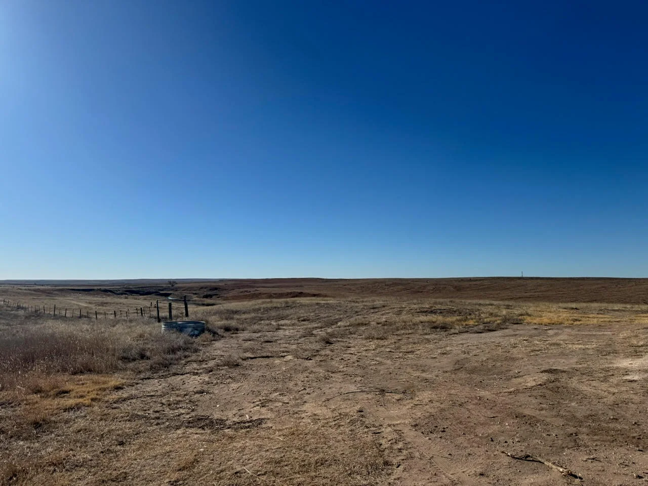Cleared rural land with graded dirt surface and fencing along property perimeter