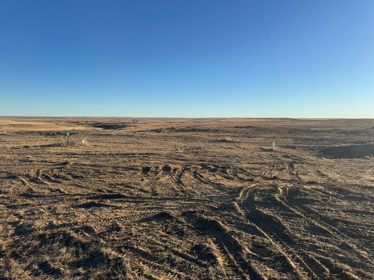 Cleared and graded land with equipment tracks visible across expansive Oklahoma property