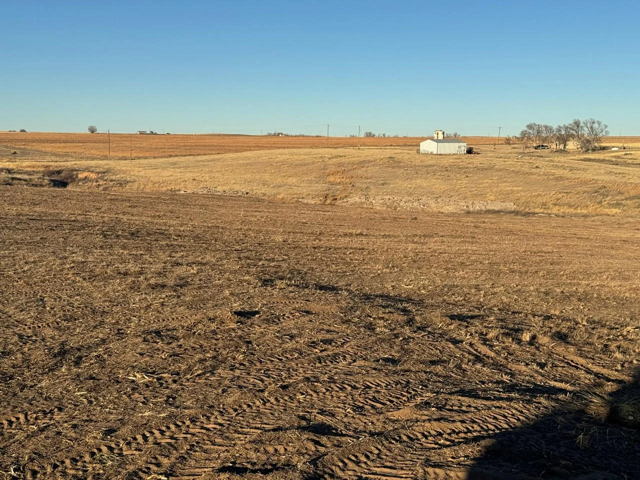 Graded dirt lot with equipment tracks and prepared foundation area on rural property